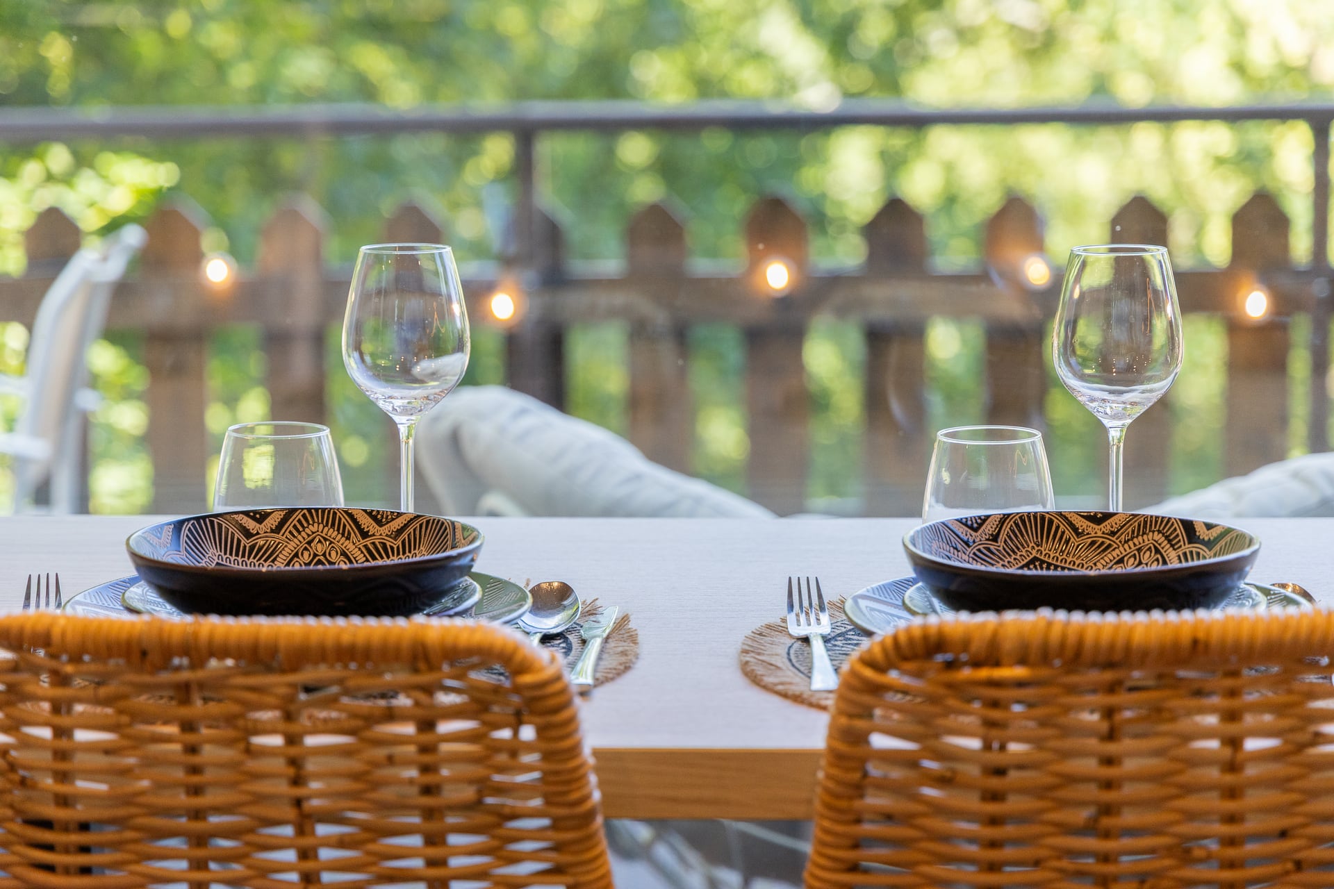 Table dressée pour deux avec la terrasse et les arbres en arrière-plan